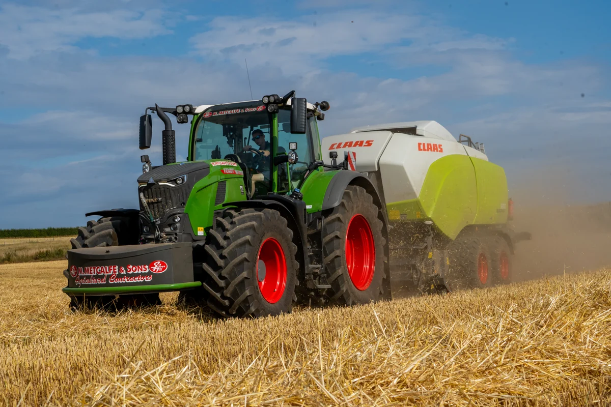 A Metcalfe tractor and baler at work, with the company name on the front weight
